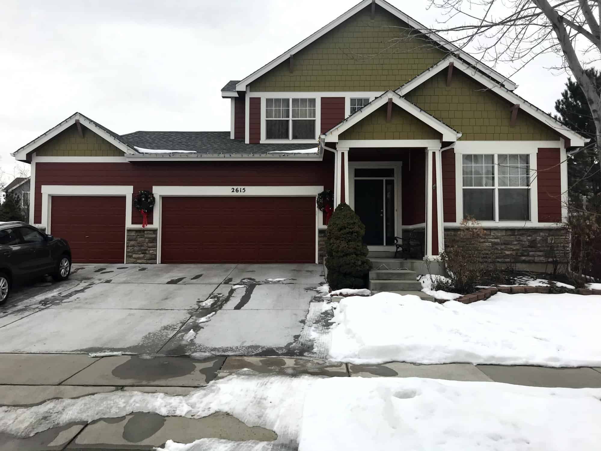 Maroon painted house exterior with garage and driveway covered in snow- painting company in Arvada, CO