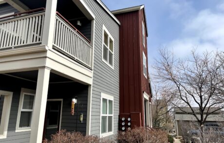 Gray and Burgundy Exterior Residential Home Gray and burgundy painted exterior residential home with white-trimmed windows, upper deck with white railings, and metal