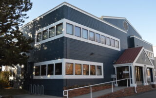 Navy Blue Commercial Building Exterior Navy blue painted two-story commercial building with white-trimmed multi-pane windows, red brick base, and white metal