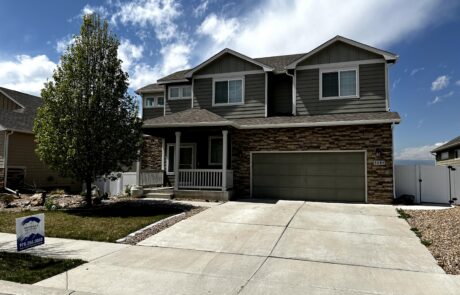 Gray Siding Exterior Residential Home Two-story residential home with dark gray fiber cement siding, stone veneer base, white front porch, and dark garage doors
