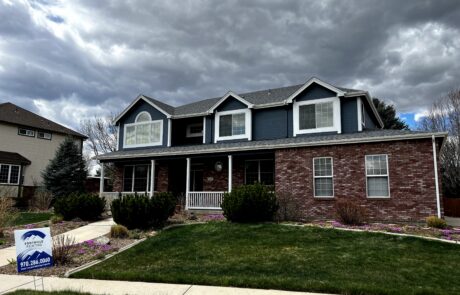 Dark Blue and Brick Exterior Home Two-story residential home with dark blue fiber cement siding upper level, red brick lower level, white-trimmed windows, and