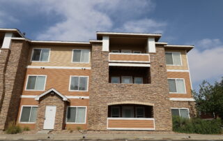 Tan And Brick Commercial Building Tan fiber cement siding with brick veneer multi-story commercial building, white-trimmed windows, and horizontal accent bands