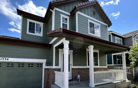 Sage Green Exterior Residential Home Sage green and white painted two-story residential home with dark brown roof, white-trimmed windows, white front porch