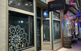Commercial Storefront Exterior Painting Cream and blue painted commercial storefront with large window displays, black signage, and brick upper facade at night