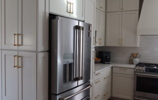 Gray Painted Kitchen Cabinets Gray painted kitchen cabinets with brass hardware, stainless steel refrigerator, and white subway tile backsplash