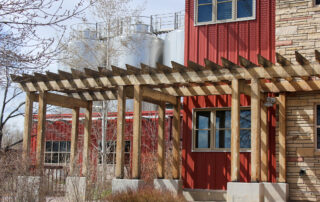 Red Painted Residential Exterior Red painted residential exterior with wood pergola, stone veneer base, blue-trimmed windows, and natural wood framing