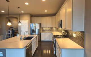 Stunning White Kitchen Cabinet Painting and Refinishing A beautifully updated kitchen featuring freshly painted white cabinets, dark floors, and stainless steel appliances.