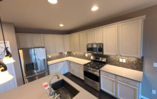 Complete Kitchen Cabinet Painting Transformation with White Finish Overhead view of a modern kitchen with new white painted cabinets, dark wood floors, and stainless steel appliances.