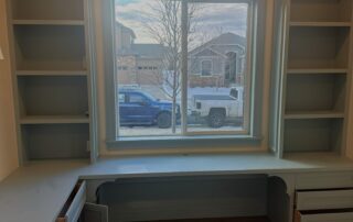 Light Blue Gray Built In Desk and Bookshelf Painting Freshly painted light blue gray built in desk with custom bookshelves surrounding a window in a modern home office.