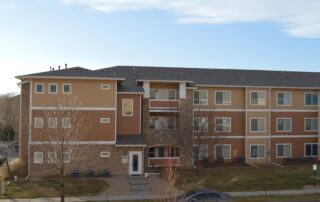Commercial Apartment Building Exterior Painting Project Exterior view of a large multi story apartment building with tan and brown siding, showcasing commercial painting expertise.