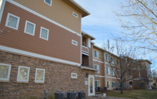 Tan And Burgundy Residential Exterior Tan fiber cement siding with burgundy brick base, white-trimmed windows, and white horizontal accent band on two-story