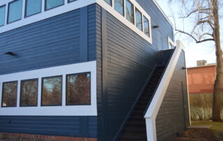 Commercial Building Exterior Painting Services Modern commercial building with dark blue exterior paint, white trim, and an outdoor staircase.