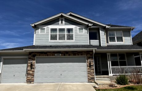 Expert Exterior House Painting for Siding and Stone Accents A modern two story house with light blue siding, stone accents, and gray garage doors, ready for exterior painting.