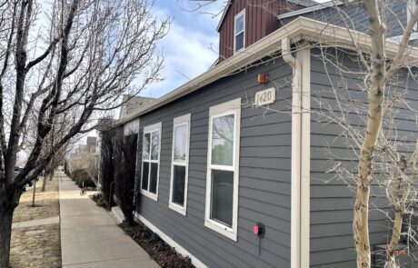 Quality Exterior Siding and Trim Painting Services Side view of a residential house with dark gray siding and crisp white trim, demonstrating quality exterior painting.