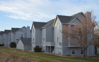 Professional exterior painting for multi family residential complexes and HOAs A row of multi family residential buildings with light gray siding and white trim, perfect for HOA painting projects.