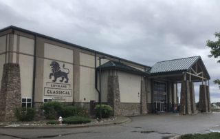 Commercial Exterior Painting for Schools and Institutions Exterior view of Loveland Classical Schools building with stucco walls, stone accents, and a covered entrance for commercial painting.