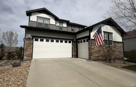 Modern Home Exterior Painting with Gray and White Finish A modern two story house with fresh dark gray siding, white trim, and stone accents.
