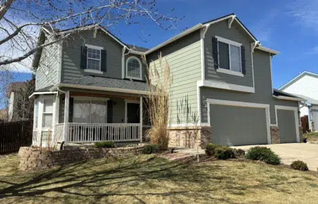 Completed exterior house painting project enhancing curb appeal Wide view of a beautifully painted residential home, featuring green siding, white trim, and an inviting front porch.