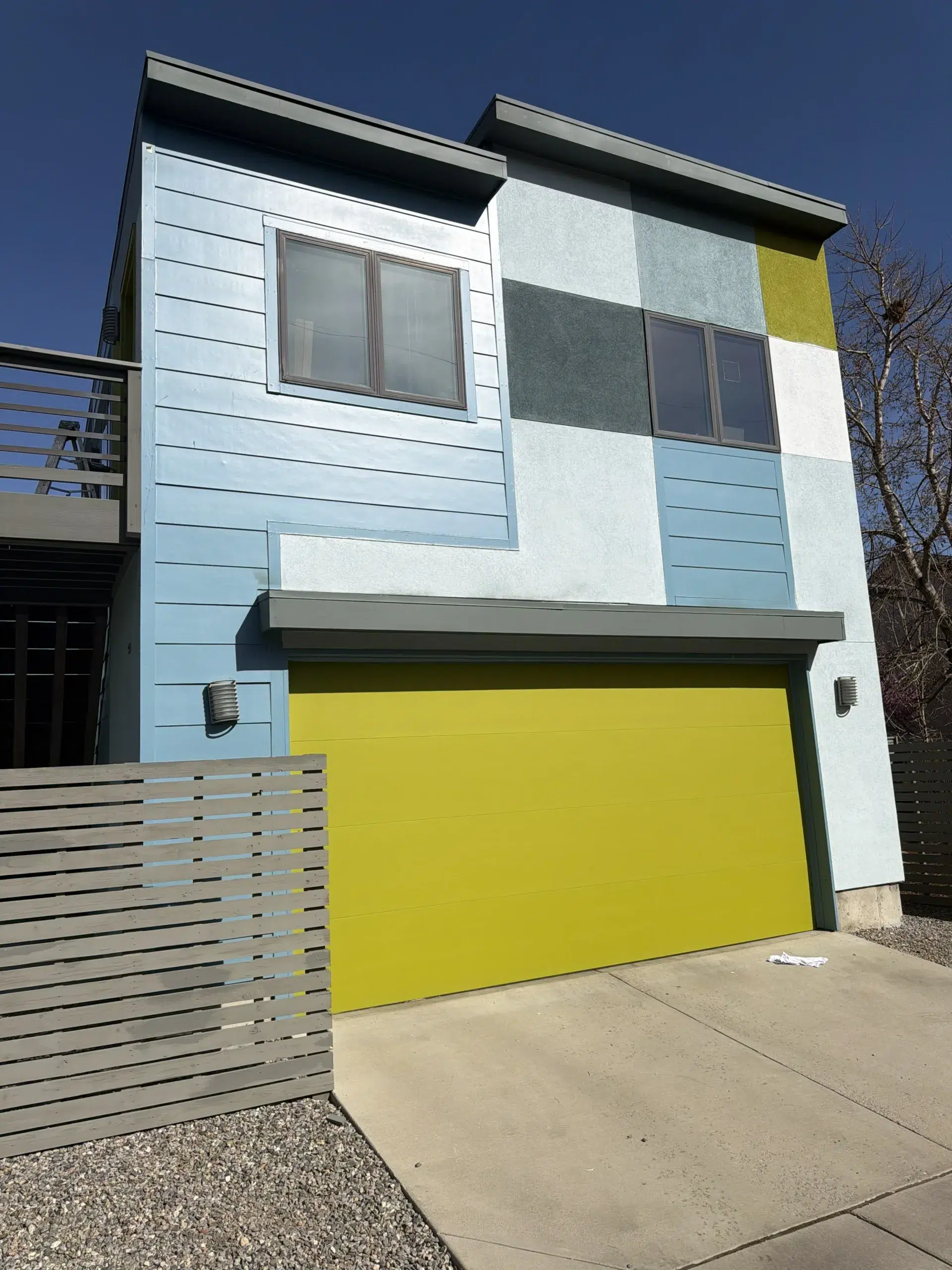 Contemporary Home Exterior Painting with Vibrant Colors and Yellow Garage Modern house with blue, white, gray, lime green panels, and a bright yellow garage door.