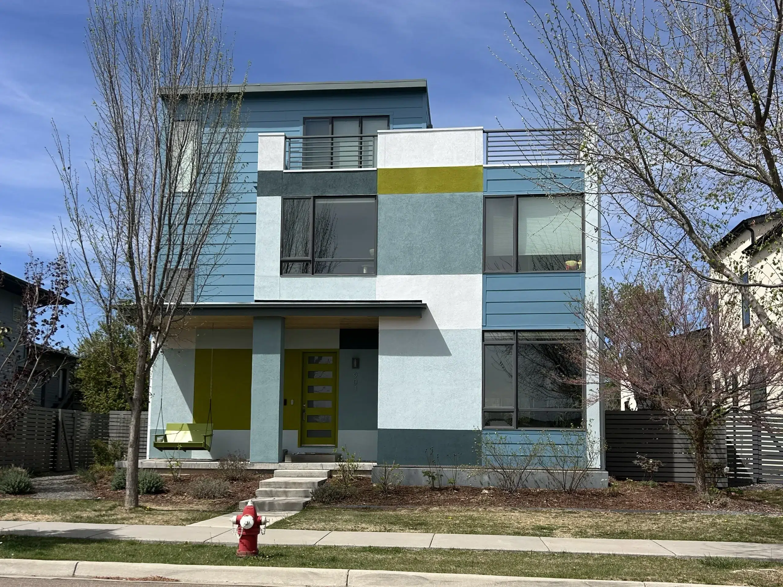 Modern Home Exterior Painting with Multi Color Design A contemporary multi story house showcasing a vibrant exterior paint job with blue, white, and lime green sections.