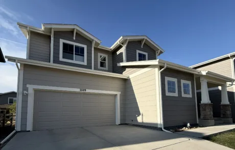 Modern Home Exterior Painting with Gray Siding and White Trim Modern two story house with light gray siding, darker gray accents, white trim, under a clear blue sky.
