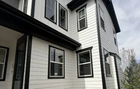 Modern Farmhouse Exterior Repaint – White Siding with Black Trim Two-story modern farmhouse with freshly painted white board-and-batten siding and black window trim after exterior repaint