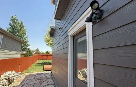 Expert Side Exterior House Painting and Siding Refresh Side of a residential home featuring freshly painted dark gray siding and white door trim.