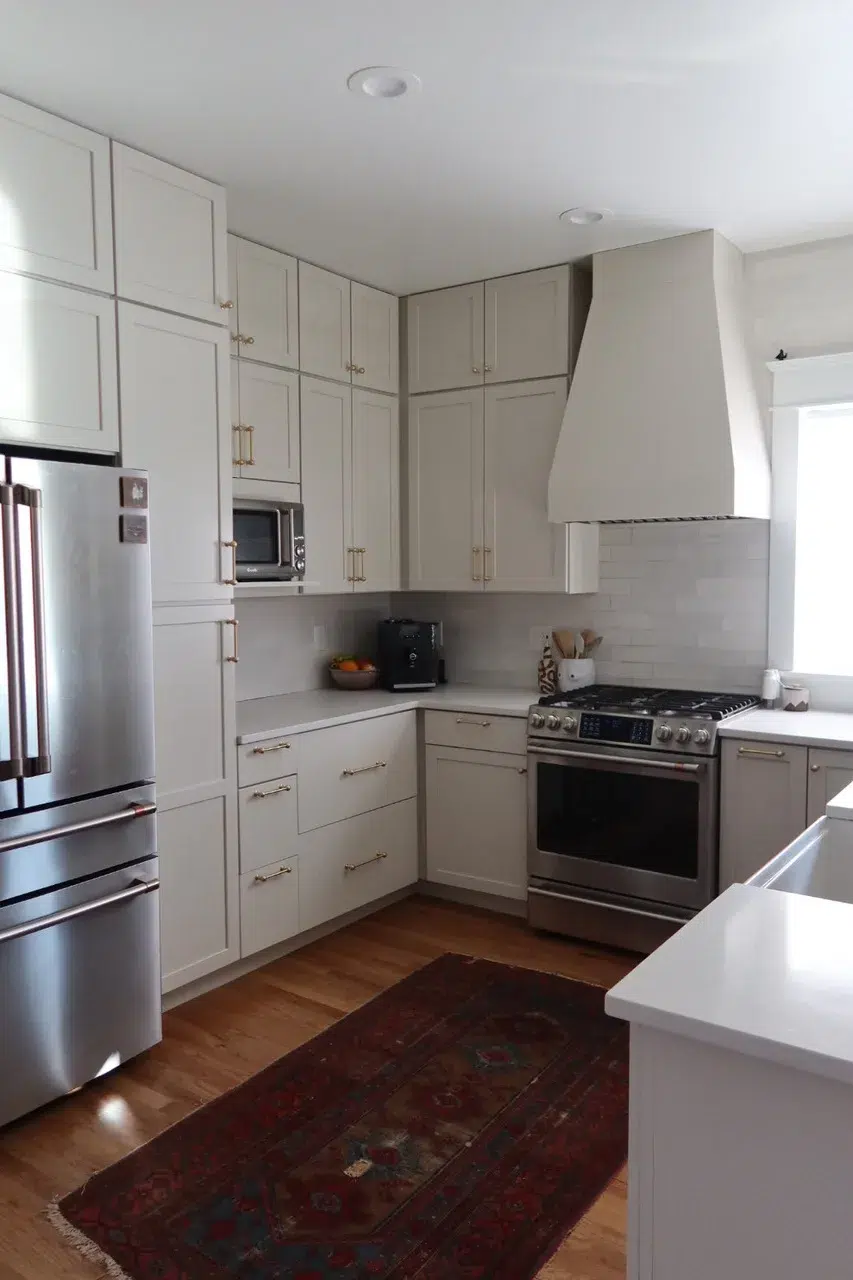 Cream Kitchen Cabinets Painted Cream-painted kitchen cabinets with shaker-style doors, brushed gold hardware, white subway tile backsplash, and stainless