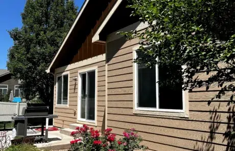 Tan Fiber Cement Siding Home Tan fiber cement siding residential home with white-trimmed windows, dark roof overhang, and black gable accent