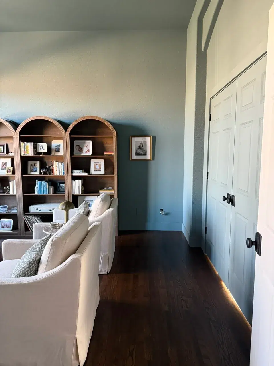 Two-Tone Accent Interior Painting Light gray and teal two-tone painted residential interior with white trim doors, wood shelving, and dark hardwood flooring