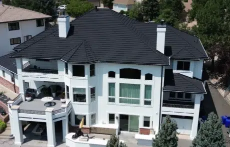 White and Black Residential Exterior White fiber cement siding two-story home with dark metal roof, black trim, brick base, and manicured landscaping in Colorado