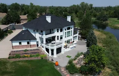White Painted Luxury Home Exterior White painted two-story residential home with black roof, brick base, multiple balconies, and riverside setting