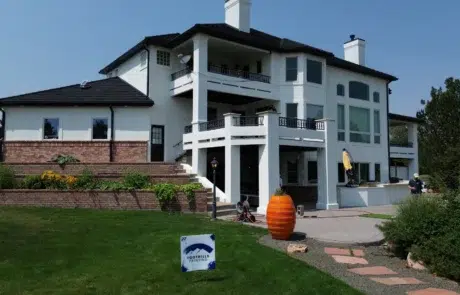 White Painted Two-Story Home White painted two-story residential home with black roof, white columns, multiple balconies, and brick base in Colorado