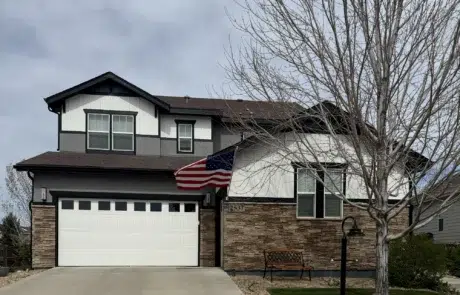 Black and White Residential Home Exterior Two-story residential home with black and white fiber cement siding, dark roof, stone veneer base, white garage door, and