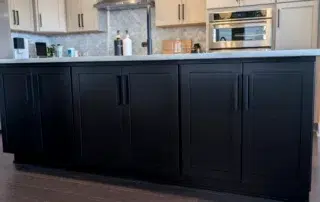 Black Kitchen Island Cabinets Black painted kitchen island with shaker-style cabinet doors and brushed nickel hardware in residential kitchen
