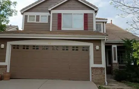 Tan And White Two-Story Residential Home Tan fiber cement siding two-story home with white trim, burgundy shutters, brown garage door, and brick base