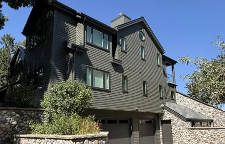 Black Fiber Cement Siding Home Black fiber cement siding two-story residential home with stone veneer base, black trim, multiple windows, and peaked roof