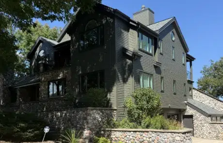 Dark Gray Fiber Cement Siding Home Dark gray fiber cement siding two-story residential home with black trim, stone veneer base, multiple windows, and peaked