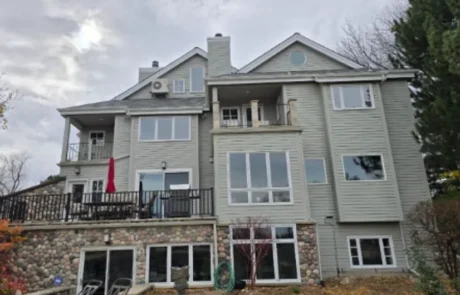 Light Gray Fiber Cement Siding Home Light gray fiber cement siding multi-level home with white-trimmed windows, stone veneer foundation, dark roof, and deck