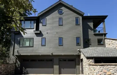 Light Gray Fiber Cement Siding Home Light gray fiber cement siding two-story residential home with dark trim, stone veneer base, multiple windows, and dark roof.