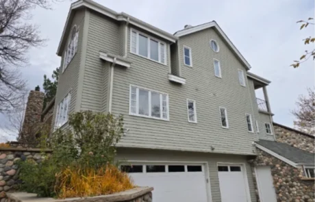 Sage Gray Fiber Cement Siding Home Sage gray fiber cement siding two-story home with white-trimmed windows, white garage doors, and stone veneer base